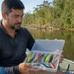 Pescador escolhendo isca artificial para tucunaré em caixa de pesca
